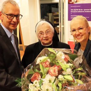 Dr. Klaus Findt, Ärztlicher Direktor, und Franziska Schulte-Kellinghaus, Pflegedirektorin (beide Helios St. Elisabeth Klinik Oberhausen, beglückwünschen Schwester Cordula (Mitte) zu ihrem 90. Geburtstag.